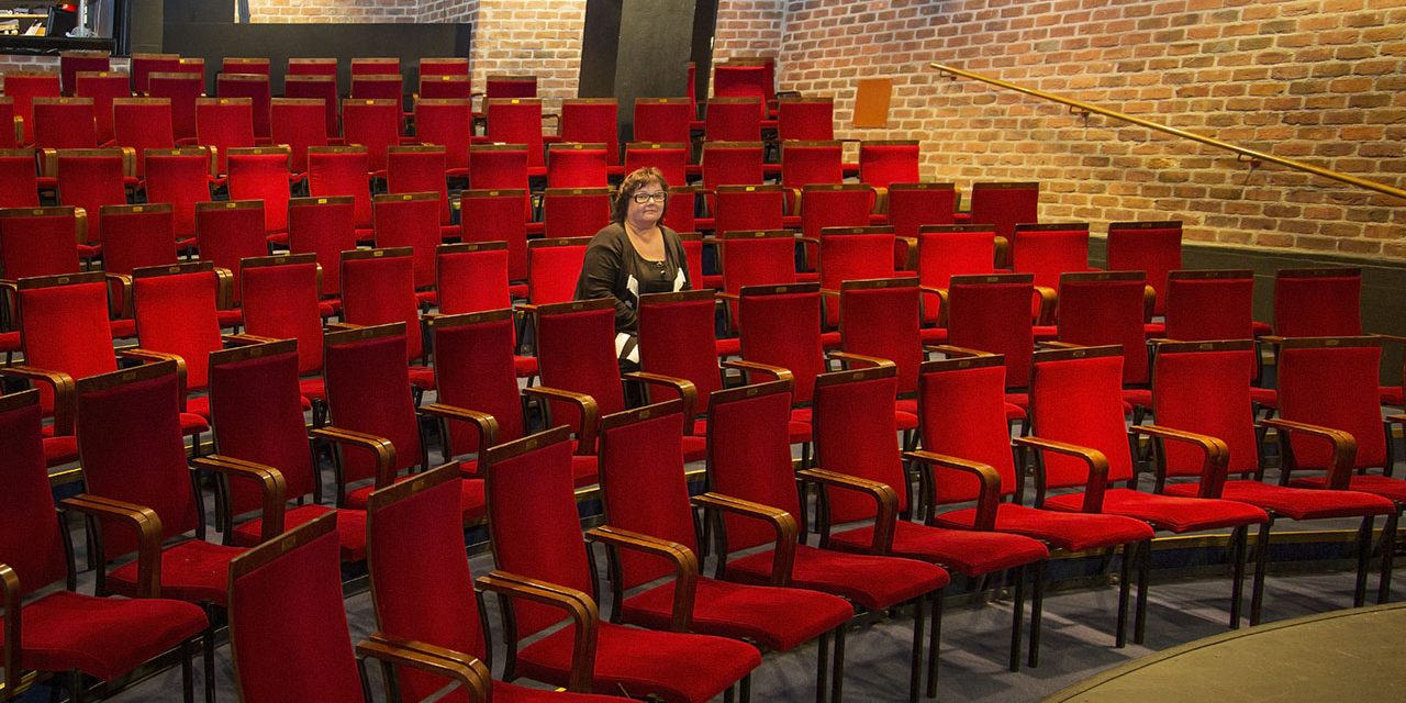 Näyttelijä Sari Mällinen istuu teatterikatsomossa.